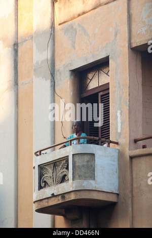 A woman stands on an art deco balcony in Havana, capitol city of Cuba Stock Photo