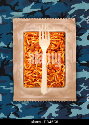 Military food rations or MRE Meals Ready to Eat on a camouflaged background. Packages open with plastic utensils. Stock Photo