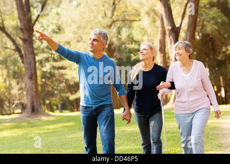 cheerful middle aged couple taking elderly mother for a walk in forest Stock Photo