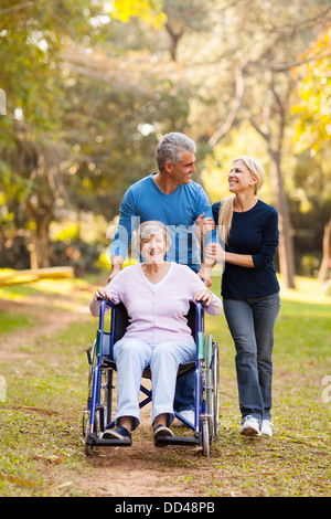 loving middle aged couple taking disabled mother for a walk outdoors Stock Photo