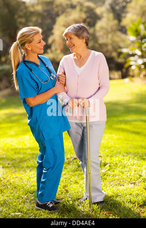 friendly middle aged caregiver talking to senior woman outdoors Stock Photo