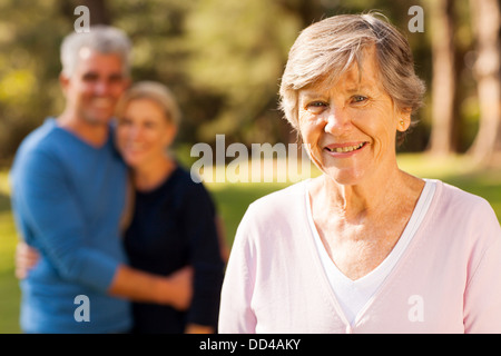 portrait of senior woman in front of middle aged son and daughter-in-law outdoors Stock Photo