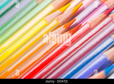 Background of rainbow coloured wooden pencil crayons arranged diagonally with a close up view of the tips Stock Photo