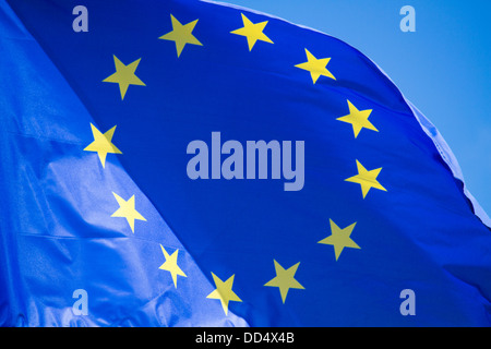 A EU flag in the wind and on the blue sky with yellow stars Stock Photo