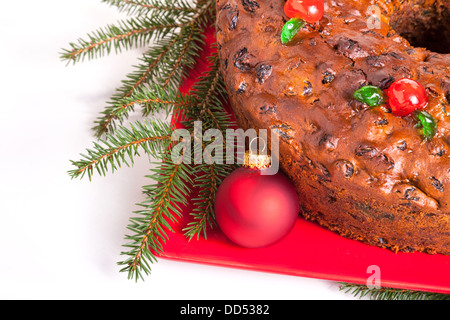 Traditional homemade Christmas fruitcake decorated with candied cherries, boughs and baubles Stock Photo