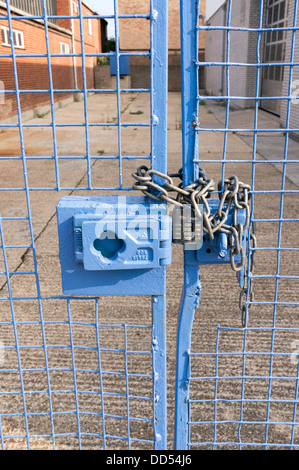 Large heavy duty combination lock padlock and chain on locked blue gates Stock Photo