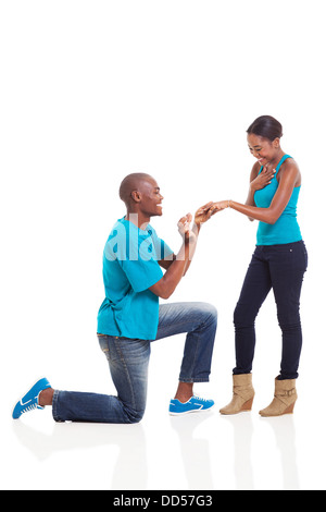 African man putting engagement ring on his excited girlfriend after she said yes isolated on white Stock Photo