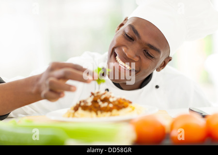 cheerful African chef decorating spaghetti Stock Photo