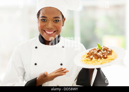 pretty African female chef holding spaghetti dish Stock Photo