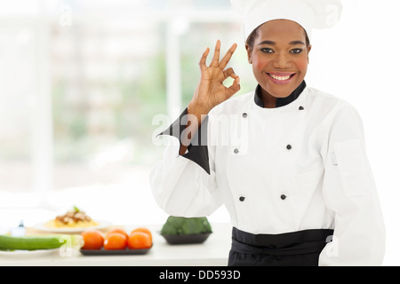 beautiful young African chef in hotel kitchen giving ok sign Stock Photo