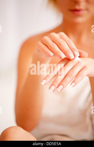 Young woman applies cream on hands over white, focus on hands Stock Photo