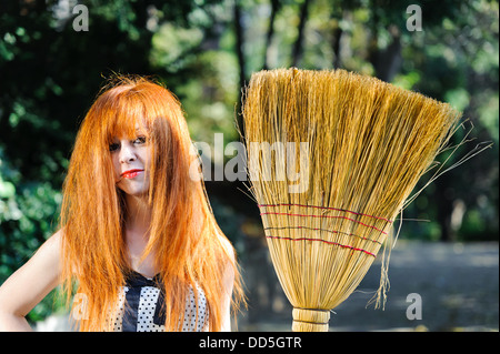Untidy red haired cute young girl with broom Stock Photo