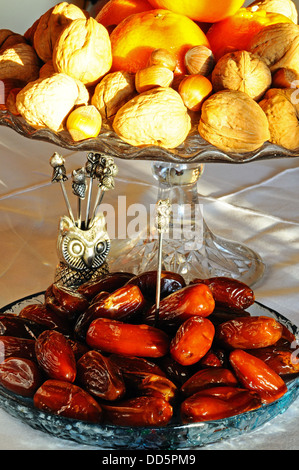 Dates in a shallow glass dish with Walnuts, hazelnuts and satsumas to the rear, England, UK, Western Europe. Stock Photo