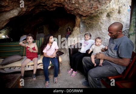 Silwan, Jerusalem, Palestinian Territory. 26th Aug, 2013. Khaled al-Zeer al-Husaini, 39, plays with his children at his cave in the east Jerusalem Arab neighbourhood of Silwan, August 26, 2013. Al-Husaini is a father of five children live in a cave, which was a stable for animals, after Israeli authorities demolished his own home 3 days ago under the pretext of building without permits Credit:  Saeed Qaq/APA Images/ZUMAPRESS.com/Alamy Live News Stock Photo