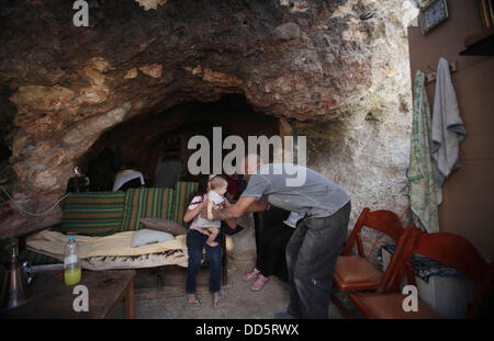 Silwan, Jerusalem, Palestinian Territory. 26th Aug, 2013. Khaled al-Zeer al-Husaini, 39, plays with his children at his cave in the east Jerusalem Arab neighbourhood of Silwan, August 26, 2013. Al-Husaini is a father of five children live in a cave, which was a stable for animals, after Israeli authorities demolished his own home 3 days ago under the pretext of building without permits Credit:  Saeed Qaq/APA Images/ZUMAPRESS.com/Alamy Live News Stock Photo