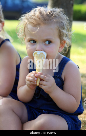 Two year old girl eating an ice cream cone on a hot day Stock Photo