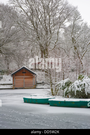 snow covered rowing boats on the boating lake at SHibden Park in Halifax,Calderdale,West yorkshire Stock Photo