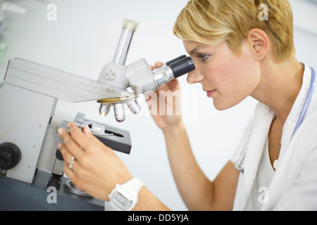Female Scientist looks through a microscope Stock Photo