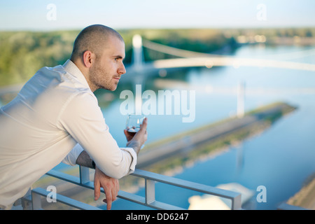 Businessman standing on hotel balcony drinking a glass of wine,Osijek, Croatia Stock Photo