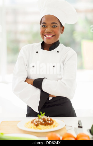 pretty female African chef with arms crossed standing in hotel kitchen Stock Photo