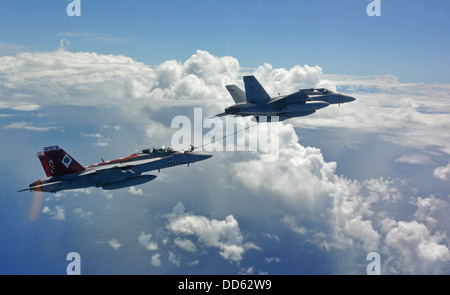 A U.S. Navy F/A-18E Super Hornet, right, assigned to Strike Fight Squadron (VFA) 27 conducts an aerial refueling with an F/A-18F Super Hornet aircraft assigned to VFA-102 during flight operations over the Philippine Sea Aug. 21, 2013. The aircraft were as Stock Photo