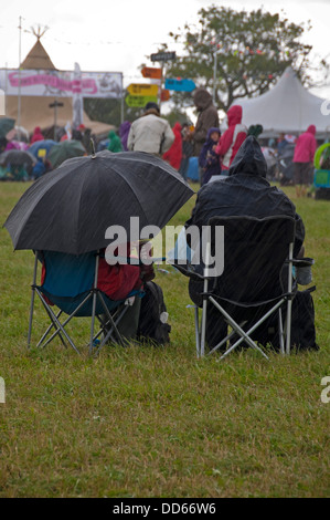 Vertical view of people at a music festival sitting in the pouring rain. Stock Photo