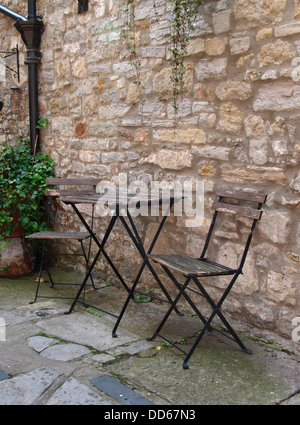Garden table and chairs against a stone wall, UK 2013 Stock Photo