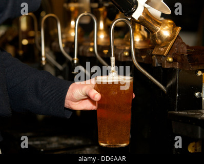 A barman pulls a pint of lager in a pub Stock Photo