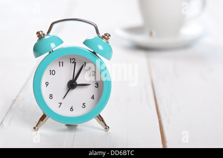 Vintage alarm clock with cup of coffee on white background Stock Photo