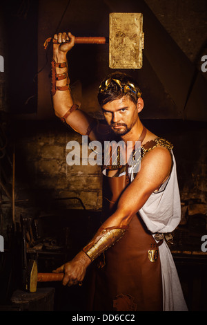 Hephaestus blacksmith in a leather apron in a forgery with the hammer and anvil Stock Photo