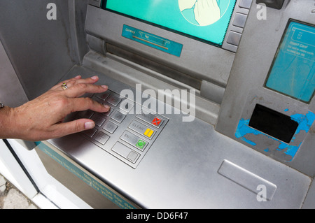 A woman entering her PIN number at a bank cash machine. Stock Photo