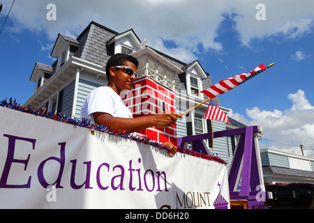 African American boy in college vehicle waving American flag during 4th of July Independence Day parades, Catonsville, Maryland, USA Stock Photo