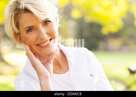 portrait of lovely middle aged woman sitting at the park Stock Photo