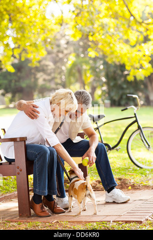 mid age couple playing with pet dog outdoors Stock Photo