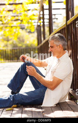 smiling middle aged man using tablet computer outdoors Stock Photo