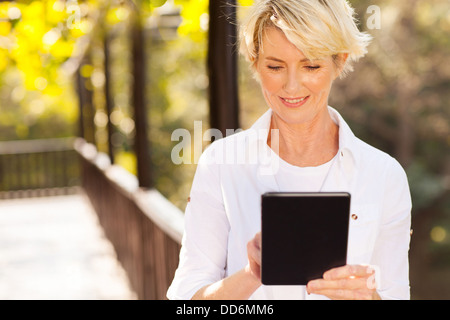 beautiful senior woman using tablet computer outdoors Stock Photo