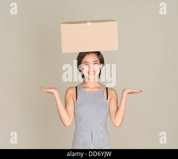 Young happy woman balance cardboard box on her head Stock Photo