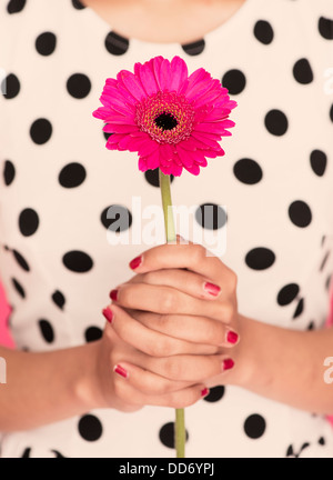 Clasped hands of woman holding a gerbera daisy Stock Photo