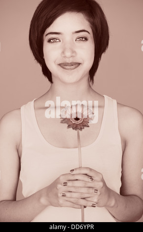 Romantic portrait of young multiracial woman holding a gerbera daisy