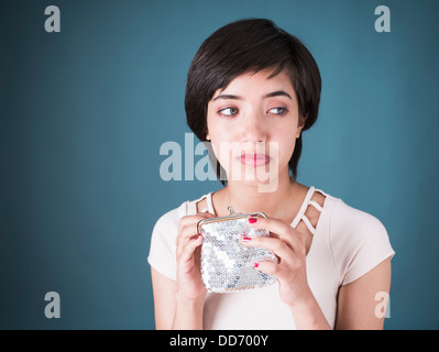 Portrait of sad young multiracial woman looking in empty silver wallet Stock Photo