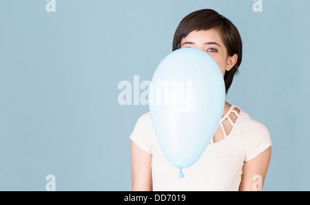 Beautiful young multiracial woman celebrating and playing with blue balloon Stock Photo