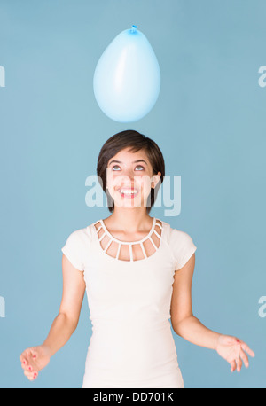 Beautiful young multiracial woman having fun with blue balloon at celebration Stock Photo