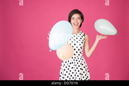 Beautiful young multiracial woman having fun with balloons at celebration Stock Photo