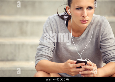 Serious female athlete listening to mp3 music during her break