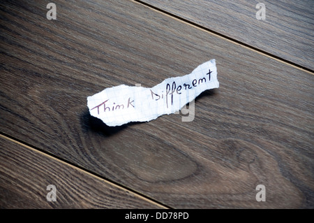 Think different written on piece of paper, on a wood background. Stock Photo