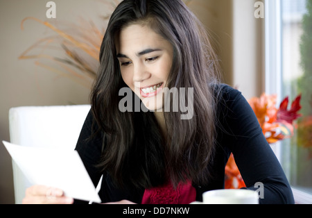 Teenage girl or young woman happily reading note in hand Stock Photo