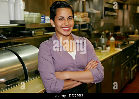 Hispanic waitress smiling in restaurant Stock Photo