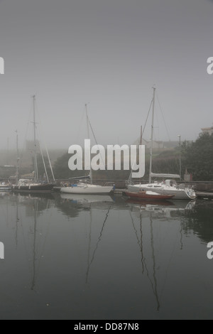 Sailing boats moored up in misty harbor Stock Photo