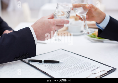Close up of business partners clinking glasses after a concluded deal Stock Photo