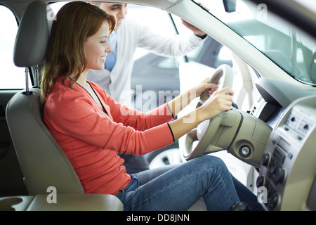 Smiling young woman being glad about her newly-bought car Stock Photo